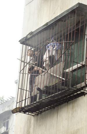 昨日，九龙坡马王乡，唐莉抱着2岁的儿子站在防盗窗上等待营救 