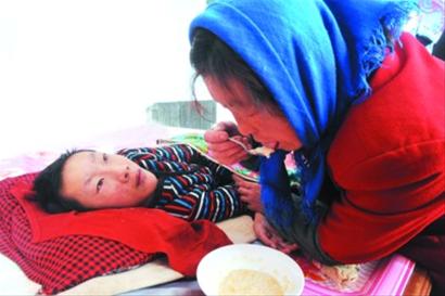 ◆母亲李淑芳用开水泡了几块饼干喂给儿子吃。在她看来，饼干就是儿子最好的营养品。