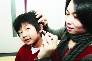 刘畅给小秋月戴上助听器。