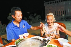儿子陈朝华给母亲吴子英夹菜。 胡杰儒 摄