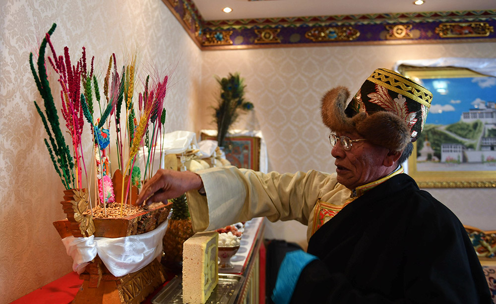 2月27日，拉萨市八一社区的次仁老人抛洒切玛盒的糌粑，祈愿新年扎西德勒。